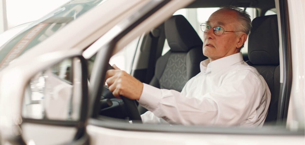 Un senior est au volant de sa voiture. Il conduit.
