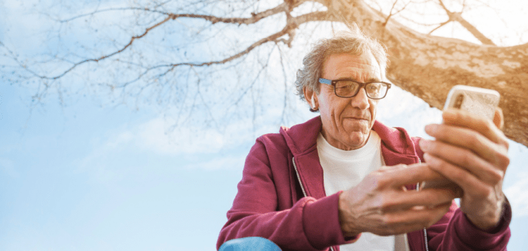 un senior est sur son téléphone, il est sur les réseaux sociaux.