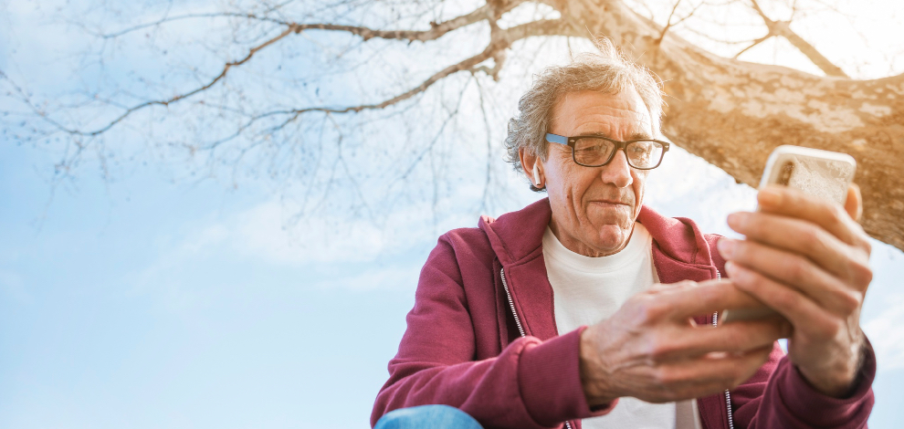 un senior est sur son téléphone, il est sur les réseaux sociaux.