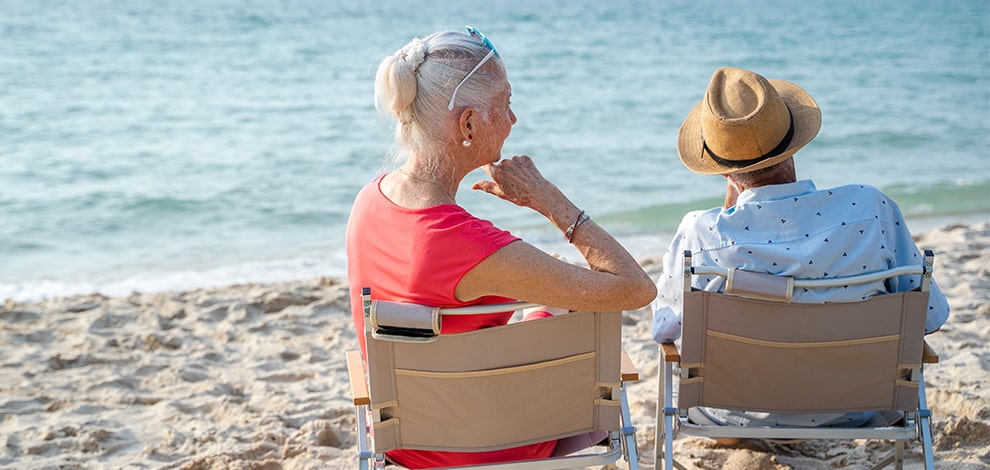 Un couple de retraités assis sur des chaises de plage, regardant la mer. Ils profitent de vacances, financées en partie par des chèques vacances pour retraités.