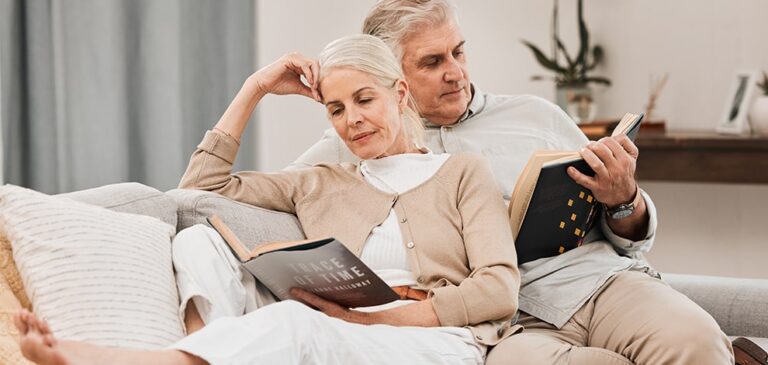 Un couple de seniors se repose sur un canapé sereinement après avoir adapté leur logement pour le vieillissement.