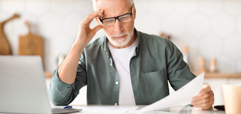 Un homme regardant des documents administratifs dans le but de connaitre sa caisse de retraite.