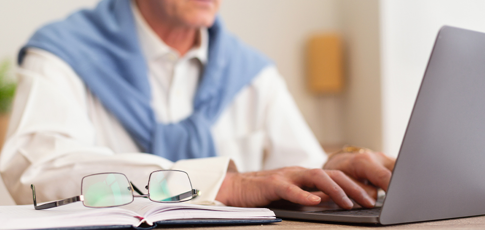 une personne agée travaillant sur son ordinateur illustrant le cumul emploi retraite