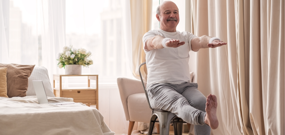 Homme pratiquant le Yoga sur chaise, en faisant une posture avec les bras levé dans sa chambre